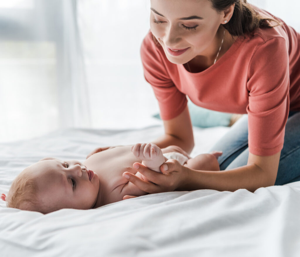 woman playing with baby on white bed