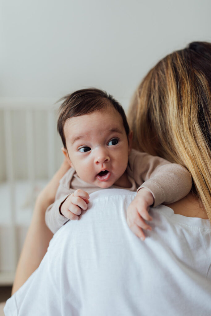 cute baby peeking over a woman's shoulder