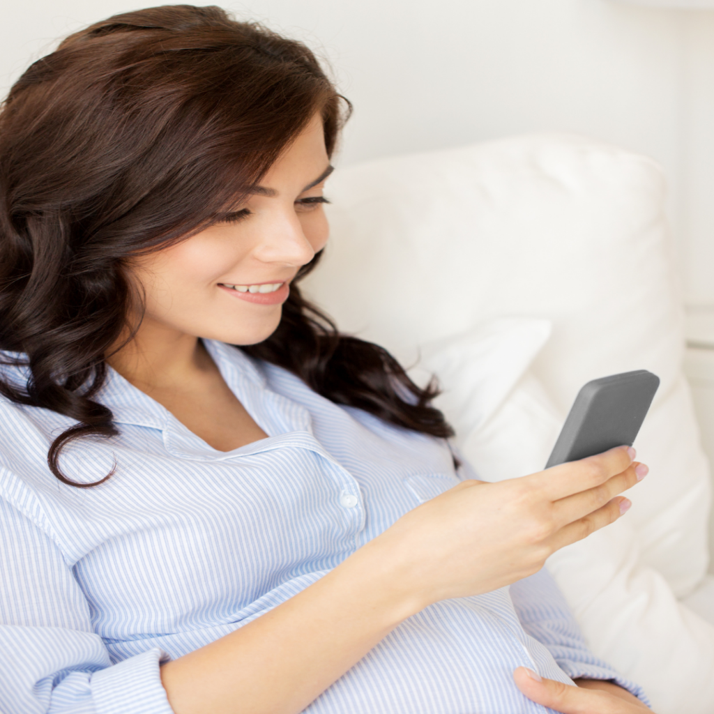 Dark haired woman texting her doula team to tell them she had bloody show. 